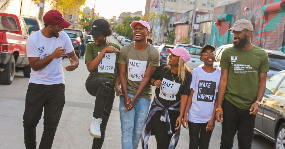 A group of friends walking down the street, all wearing shirts saying "Make It Happen". Solutions to Prevent Community Violence